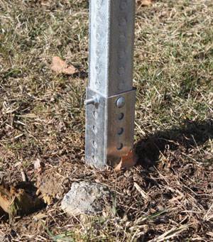 A galvanized square sign posts are embedded in the soil.