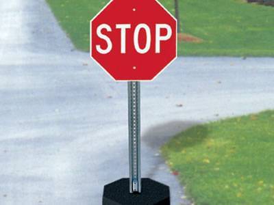 A galvanized U channel sign post with red warning board and black plastic base on the street.