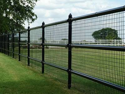 There is a welded cattle fence with several rough posts and horizontal rails on the grassland.