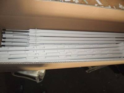 Several white electric fence posts in the carton.