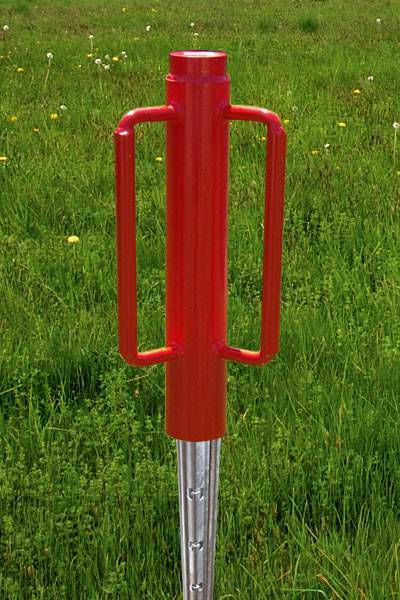 A red post driver is installing a vineyard post on the grassland with a detail of vineyard post.