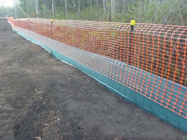 Star pickets, orange safety barrier and shade cloth are placed along the forest construction site.