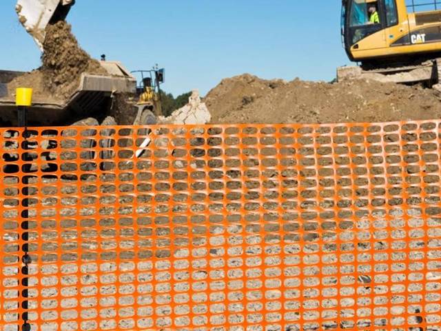Black bitumen star pickets are used in the construction site and supporting orange safety barrier.