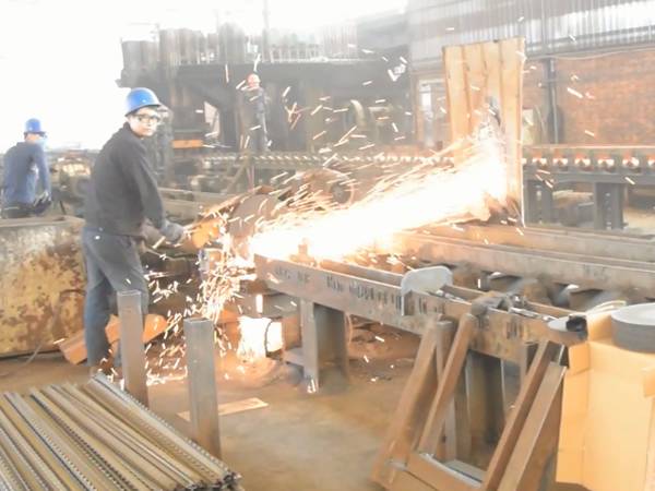 Several workers are cutting the star pickets into specified length.