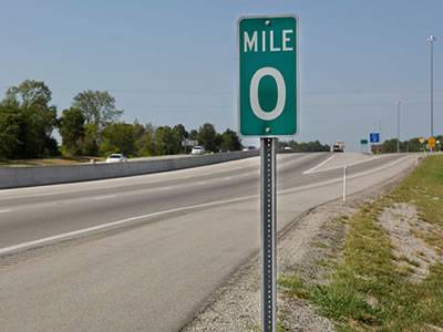 A galvanized U channel sign post with green guide board on the road.